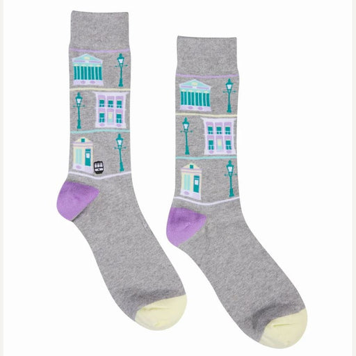 Knit socks by The Bath Sock Company featuring an illustrated pattern of Bath England landmarks including the Roman Baths and Georgian townhouses with teal lamp posts purple heels and yellow toes