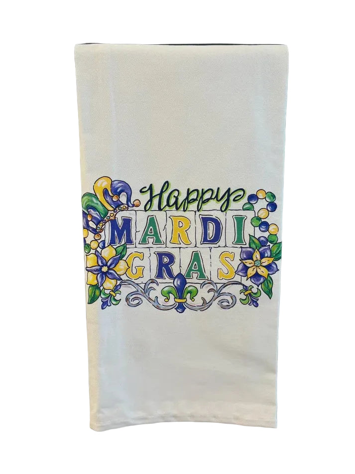 Folded white tea towel printed with "Happy Mardi Gras" in tile letters with a jester hat and fleur de lis