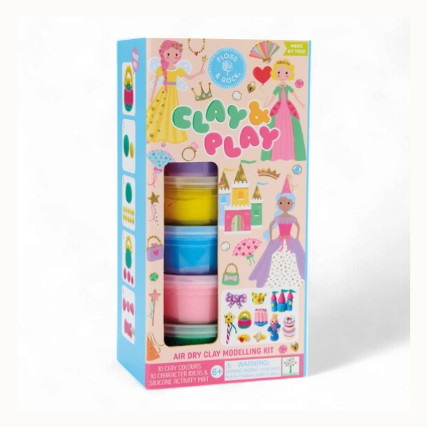 Product photography of a Floss &amp; Rock Clay &amp; Play air dry clay modelling kit featuring whimsical princesses and a colorful fairytale castle alongside stacked tubs of vibrant pink and yellow clay on a white background