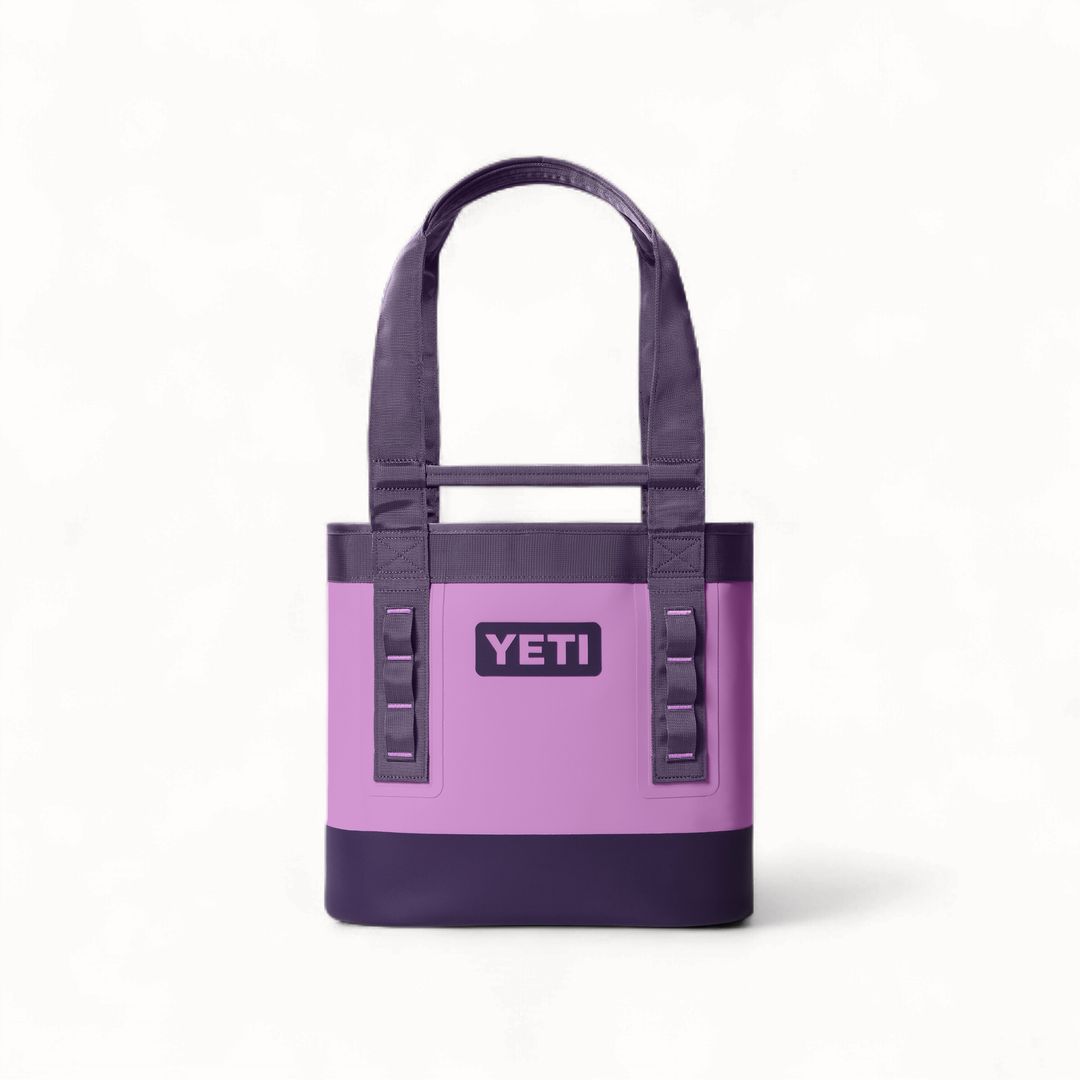 Product photography by YETI of a lilac and dark purple Camino Carryall tote bag on a white background featuring a waterproof exterior, durable webbing handles, and the iconic brand logo centered above vertical utility loops