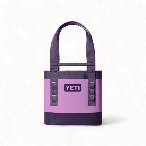Product photography by YETI of a lilac and dark purple Camino Carryall tote bag on a white background featuring a waterproof exterior, durable webbing handles, and the iconic brand logo centered above vertical utility loops