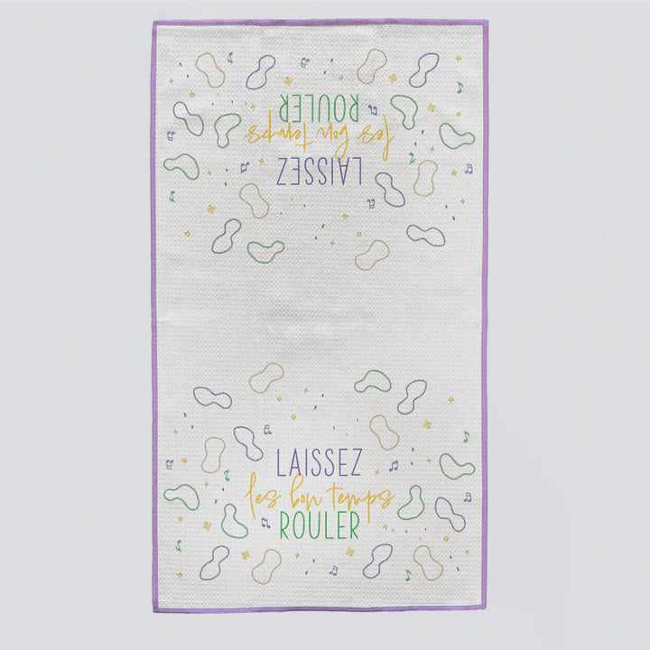 White kitchen towel with purple trim printed "Laissez les bon temps rouler" at both ends with bead outlines
