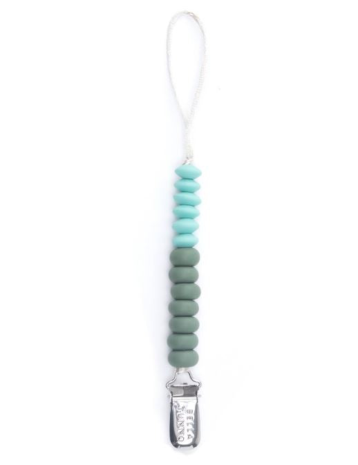 Silicone and metal pacifier clip by Bella Tunno featuring a vertical strand of teal and sage green saucer-shaped beads on a white background with a white braided cord loop and an engraved silver metal clip at the bottom