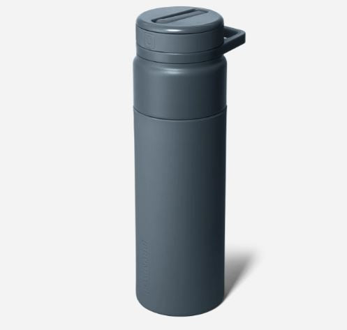 Studio product photograph of a matte slate blue LARQ reusable water bottle on a neutral white background featuring an integrated carry loop and a textured flip-top lid design