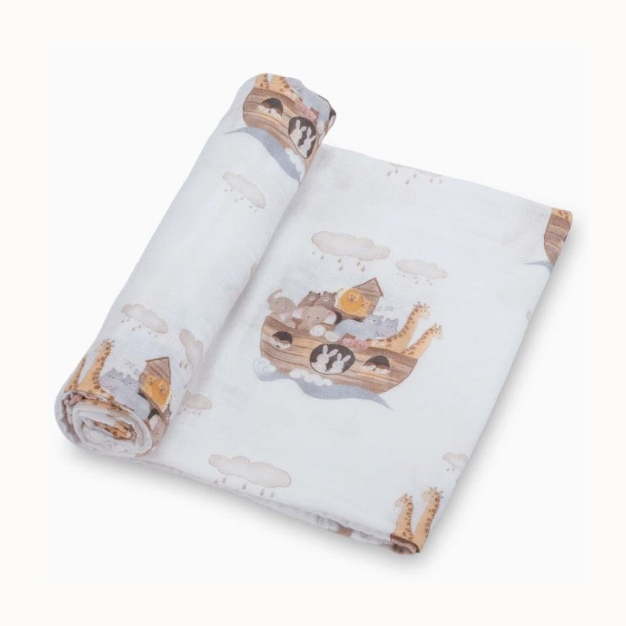 Watercolor-style printed muslin swaddle blanket depicting the iconic Noahs Ark floating on blue waves with soft rainy clouds and a variety of pastel animals including long-necked giraffes and lions peering out from the wooden deck