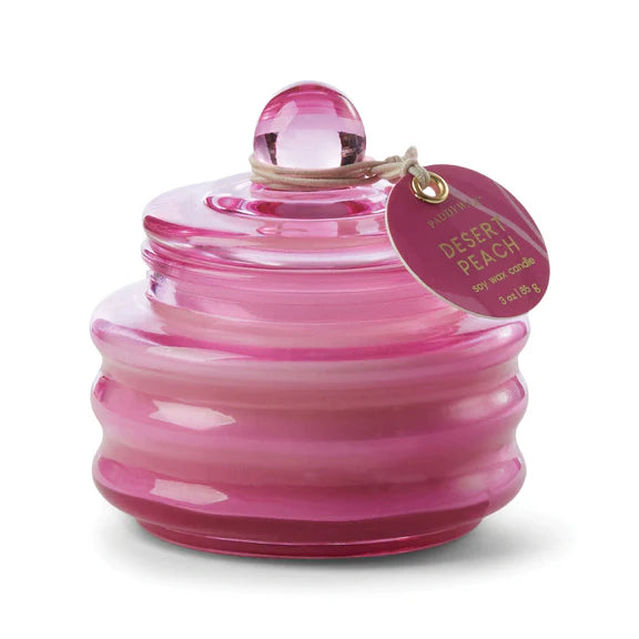 Paddywax Desert Peach soy wax candle in a translucent fuchsia ribbed glass jar featuring a spherical lid handle and a circular branded tag on a white background