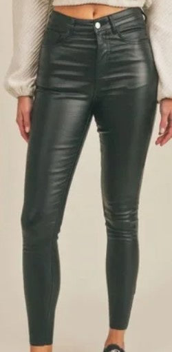 Person wearing dark green coated skinny pants with a cream sweater