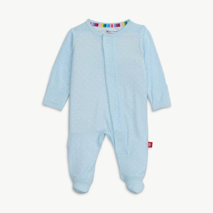 Digital product photograph of a Zutano baby footie pajama centered on a white backdrop featuring light blue fabric with white dots, a rainbow-striped inner collar, and a red brand tag