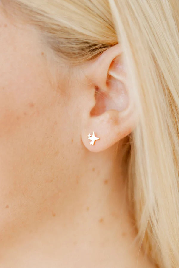Photograph of a gold North Star sparkle stud earring worn on a person&