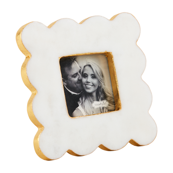 White marble scalloped square frame with gold edges holding a photo of a couple