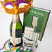Bottle of champagne, Mardi Gras mask, beads, and New Orleans cocktail book on a white background