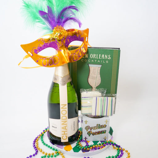 Mardi Gras-themed items including a bottle of champagne, a mask, beads, and a book titled 'New Orleans Cocktails' on a white background.
