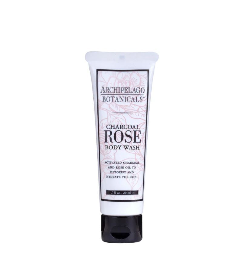 Product photograph of an Archipelago Botanicals Charcoal Rose Body Wash tube on a plain white background featuring pink floral line-art, a solid black cap, and descriptive text for charcoal and rose oil ingredients