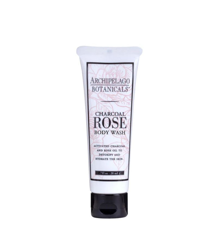 Product photograph of an Archipelago Botanicals Charcoal Rose Body Wash tube on a plain white background featuring pink floral line-art, a solid black cap, and descriptive text for charcoal and rose oil ingredients
