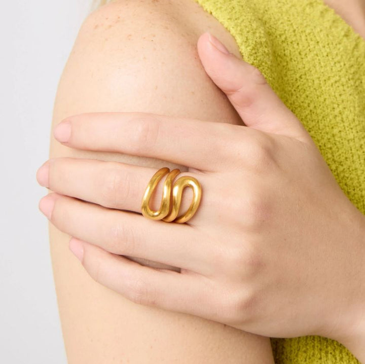 Jewelry photograph of a matte gold sculptural triple-band ring on a model&