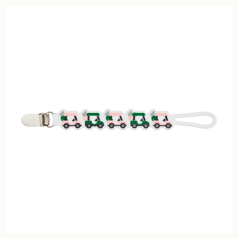 Silicone pacifier clip featuring a row of alternating pink and green golf carts with miniature golf bags on a white strap with a polished silver metal fastener