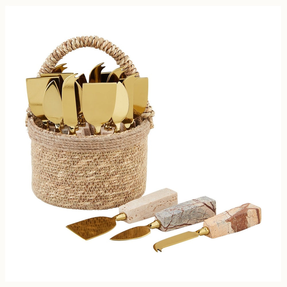 Gold-finished stainless steel and natural stone cheese knife set featuring rectangular handles with unique earthy veining and various blade shapes displayed in a textured woven seagrass basket on a clean white background
