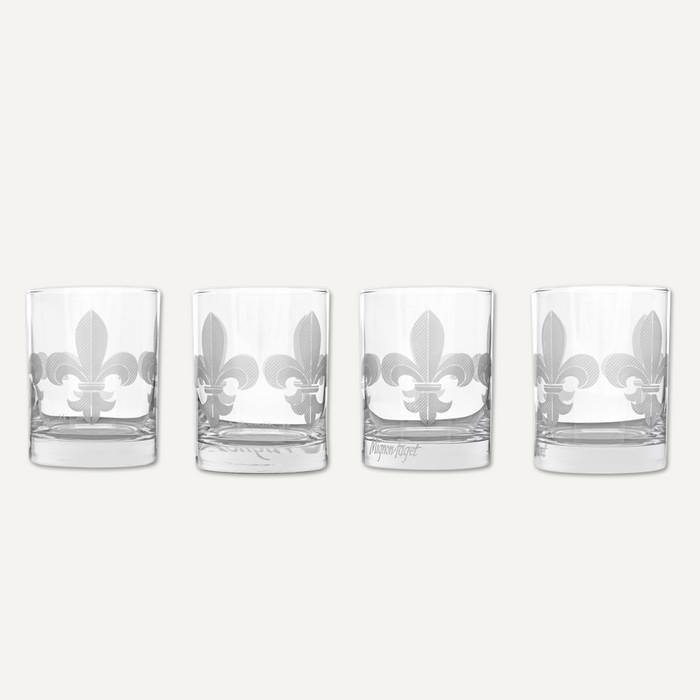 Etched glassware by Mignon Faget featuring a set of four rocks glasses against a neutral background showcasing the iconic New Orleans fleur-de-lis with a frosted cross-hatched pattern and heavy weighted bases