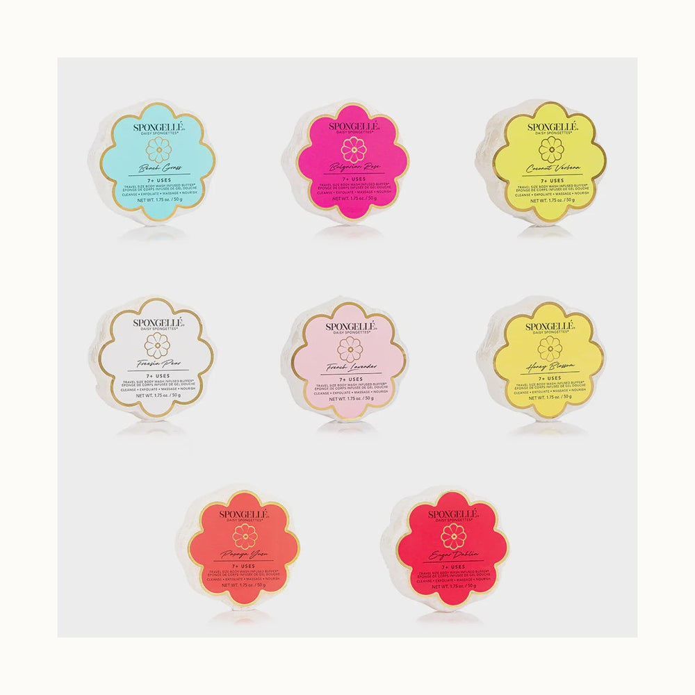 Product photograph by Spongellé of eight flower-shaped Daisy Spongette buffers arranged on a neutral background featuring vibrant Bulgarian Rose pink and Beach Grass teal labels with scalloped edges and the iconic Spongellé brand logo