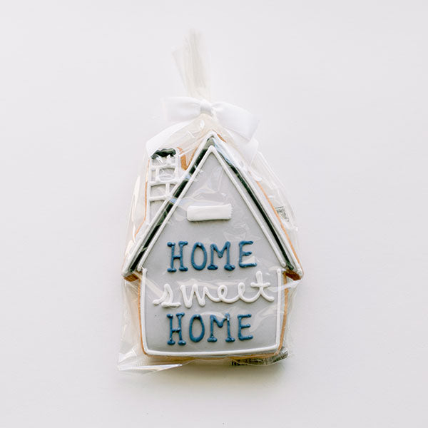 House-shaped sugar cookie iced with Home Sweet Home, wrapped in cellophane with a white bow