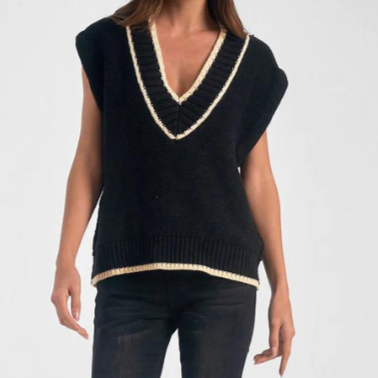 Woman wearing a black V-neck sweater vest with cream trim and black jeans