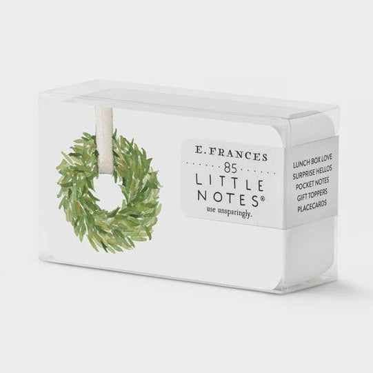 Watercolor illustration by E. Frances Paper of 85 Little Notes stationery cards in a clear box featuring a lush green leafy wreath with a white ribbon and crisp black typography