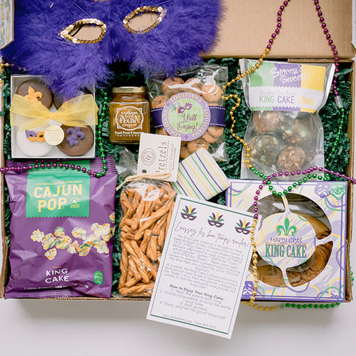 Mardi Gras king cake and snacks with a feather mask and Mardi Gras beads