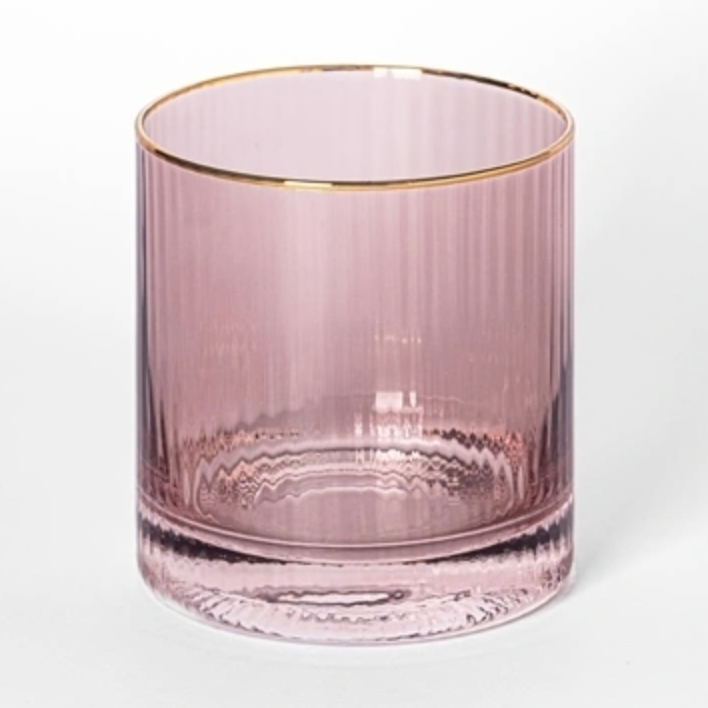 Pink tinted glass by unknown artist featuring a polished gold rim and vertical fluted texture set against a plain white studio backdrop