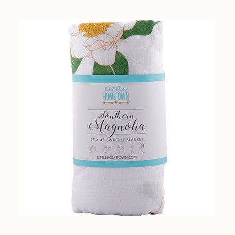 Muslin swaddle blanket by Little Hometown featuring a Southern Magnolia print with large white petals, lush green leaves, and a textured yellow center