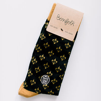 Woven crew socks by Bonfolk featuring a New Orleans theme with an iconic white St. Charles streetcar emblem and a repeating gold fleur-de-lis pattern on a black background with tan accents