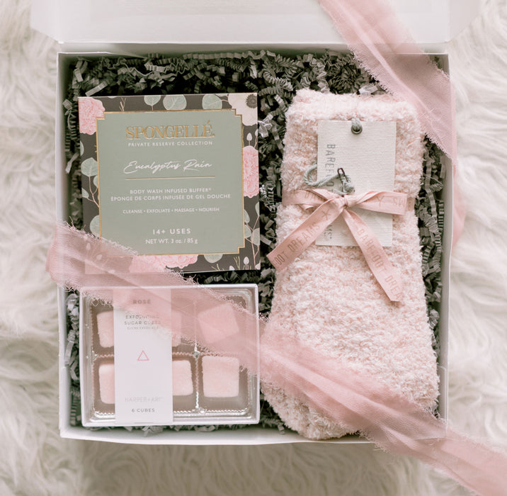 A relax gift box with Spongelle, Barefoot Dreams socks, and exfoliating sugar cubes
