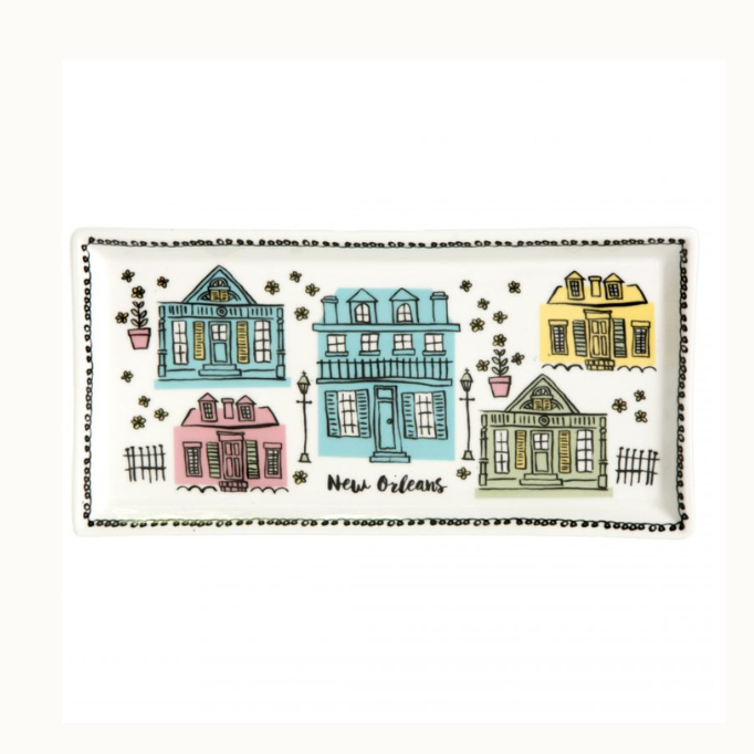Illustrated ceramic tray showcasing New Orleans French Quarter architecture with colorful Creole cottages and a balcony house featuring hand-drawn gas lanterns, pastel pink and blue tones, and a black dotted border