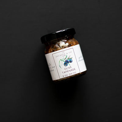 Small jar of Jocelyn &amp; Co olive tapenade on a black background