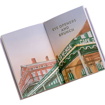 Watercolor illustration of Café Du Monde in New Orleans featuring its iconic green-and-white striped awning, red brick architecture with wrought iron balconies, and the stylized text Eye Openers and Brunch across an open book spread