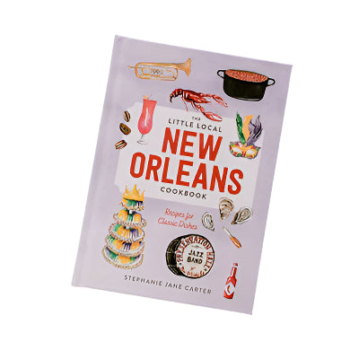 Stephanie Jane Carter’s illustrated cookbook cover for The Little Local New Orleans Cookbook features a Preservation Hall Jazz Band drum icon, a colorful tiered king cake, and a bright red crawfish against a pale lavender backdrop