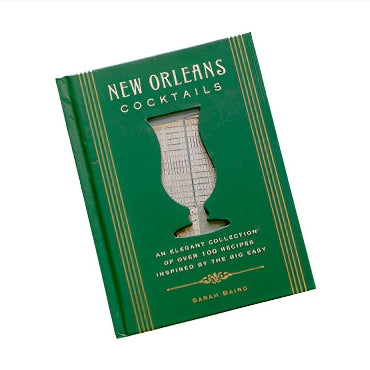 Hardcover book by Sarah Baird titled New Orleans Cocktails featuring a forest green cover with gold Art Deco typography and a hurricane glass-shaped cutout revealing the St. Louis Cathedral