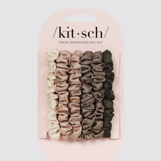 Satin scrunchies by Kitsch featuring a six-piece set of hair accessories in a neutral gradient from ivory to olive green with a lustrous ruched texture on a light pink display card